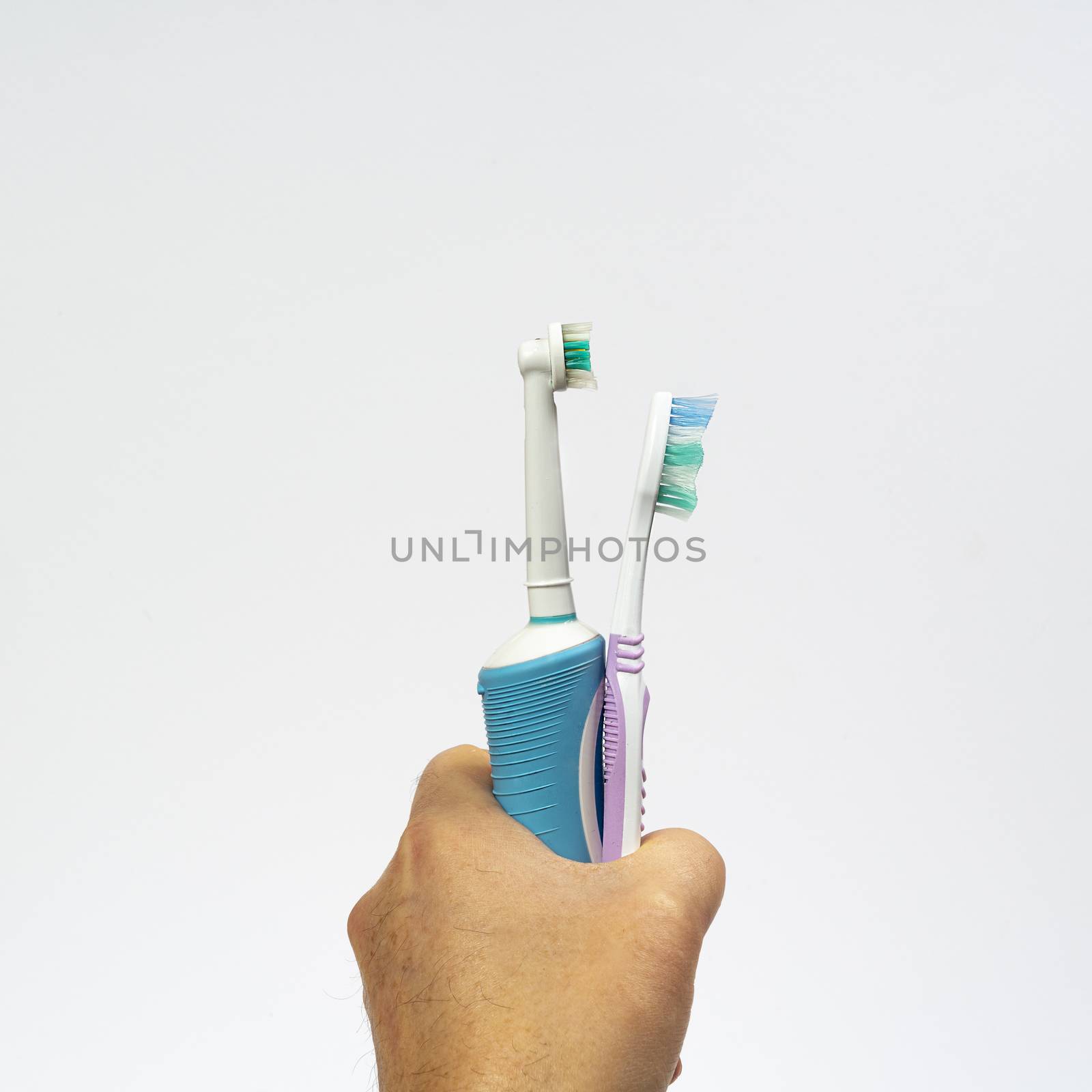 an electric toothbrush and a traditional one in hand