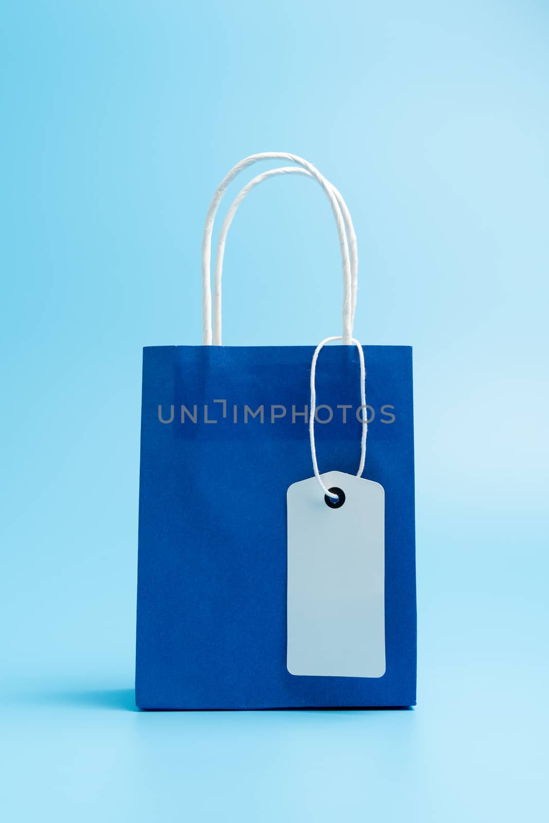 Blue shopping or gift bag isolated on blue background by Kenishirotie