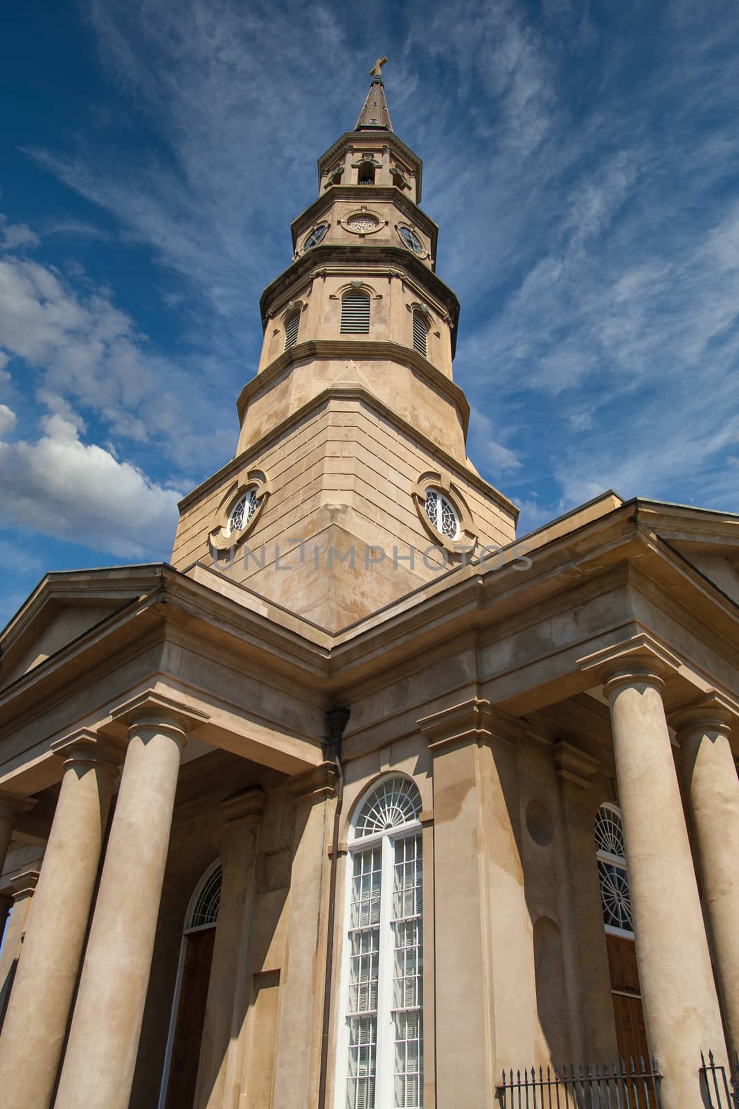 Old brown church with columns and clock tower under blue sky