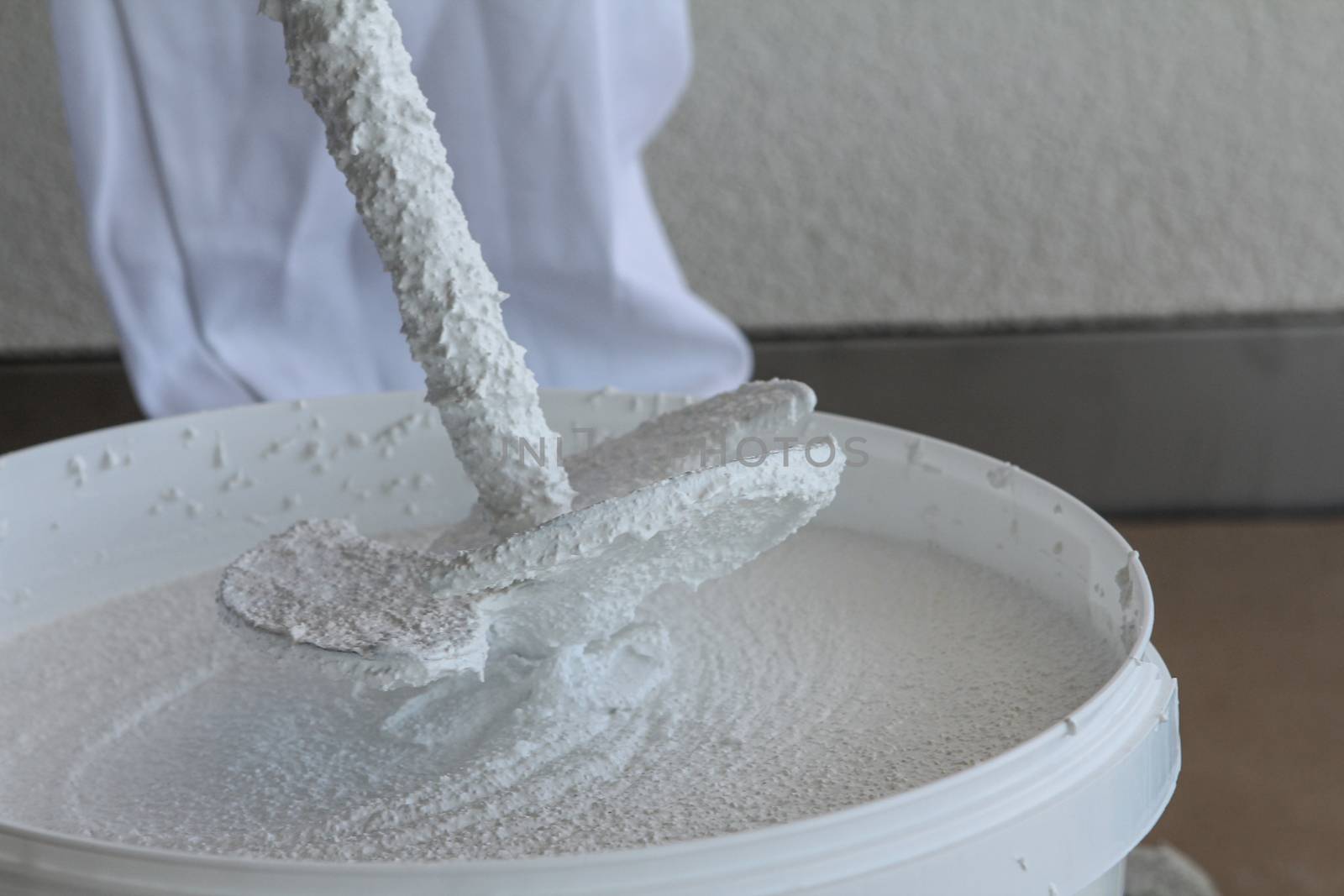 Plasterer stirring plaster in a bucket with white clothing