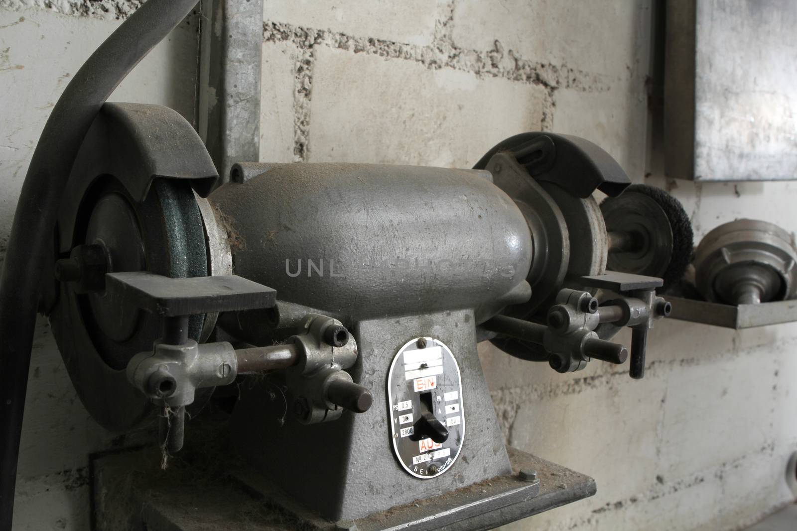Old grinding machine in an old mechanic shop. with dirty wall