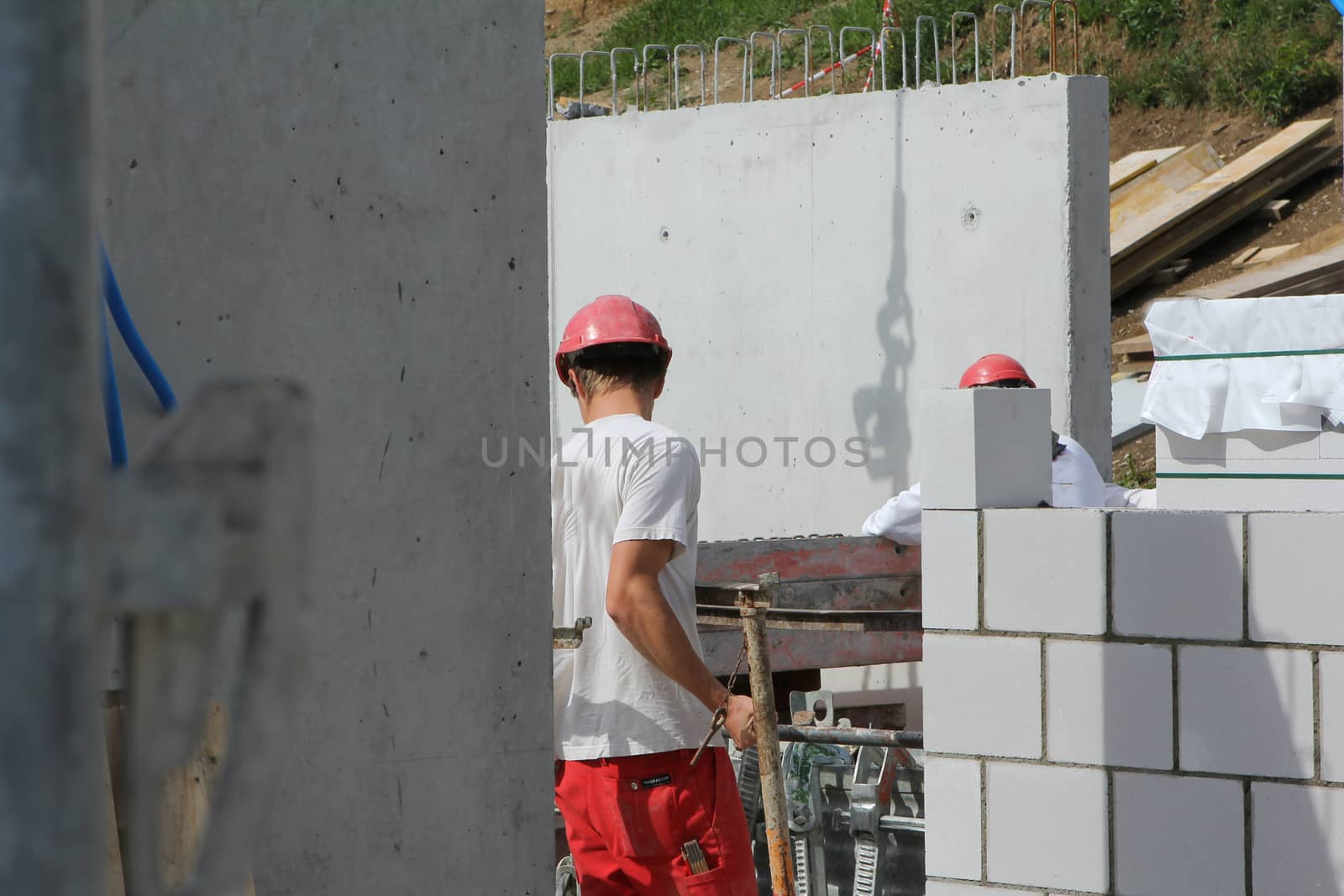Hard working people at construction site. Worker with helmet and red pants