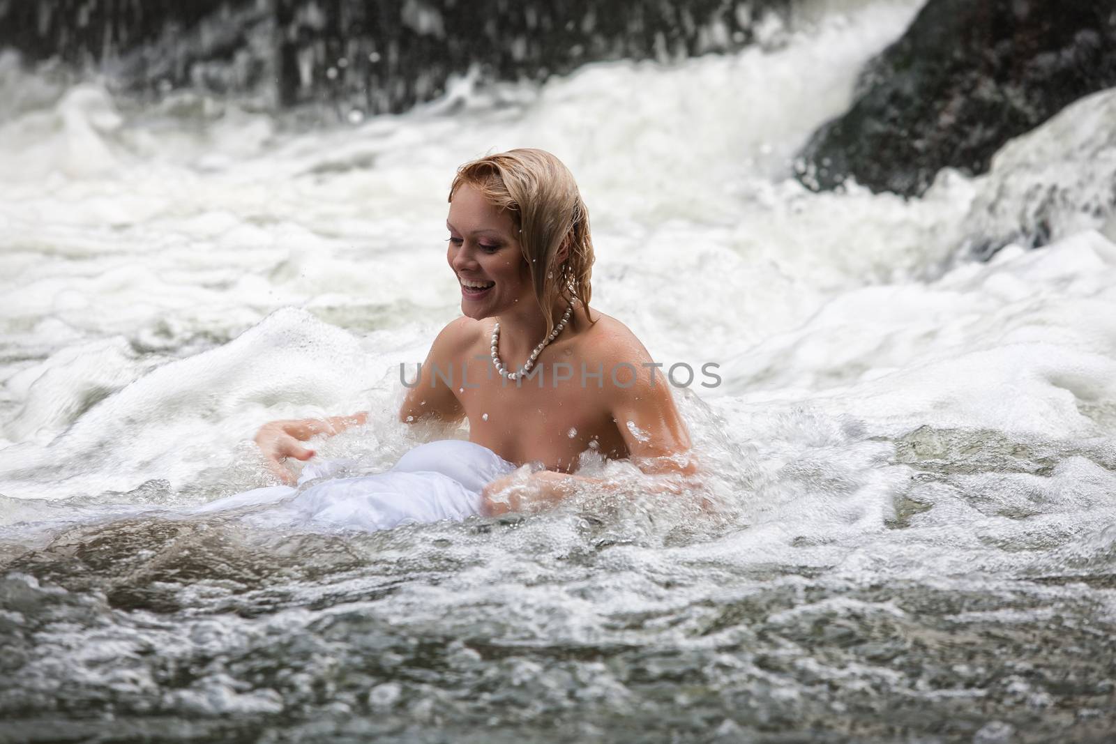 Young naked woman swimming in a river