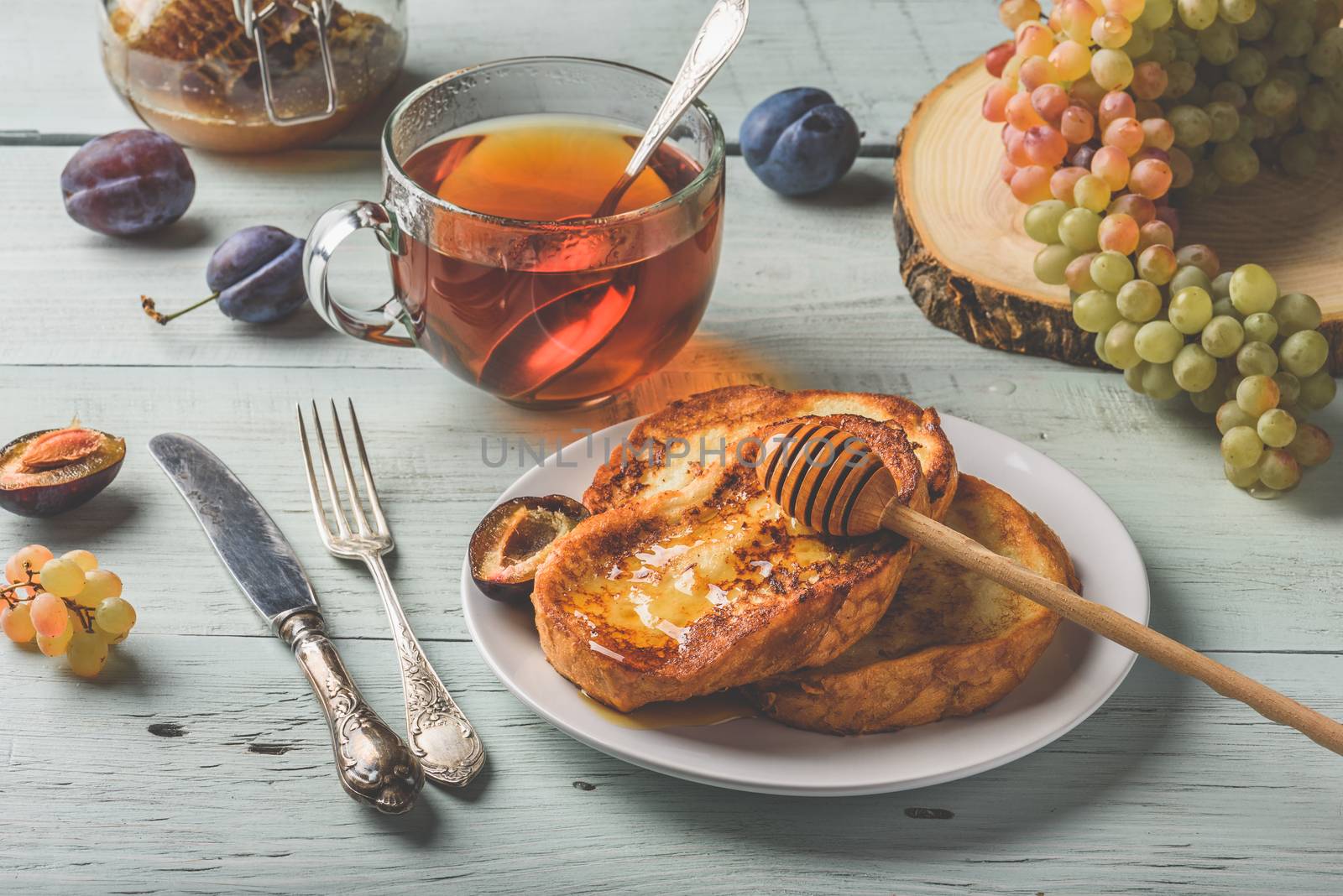 Healthy breakfast concept. French toasts with honey, fruits and tea over white wooden background