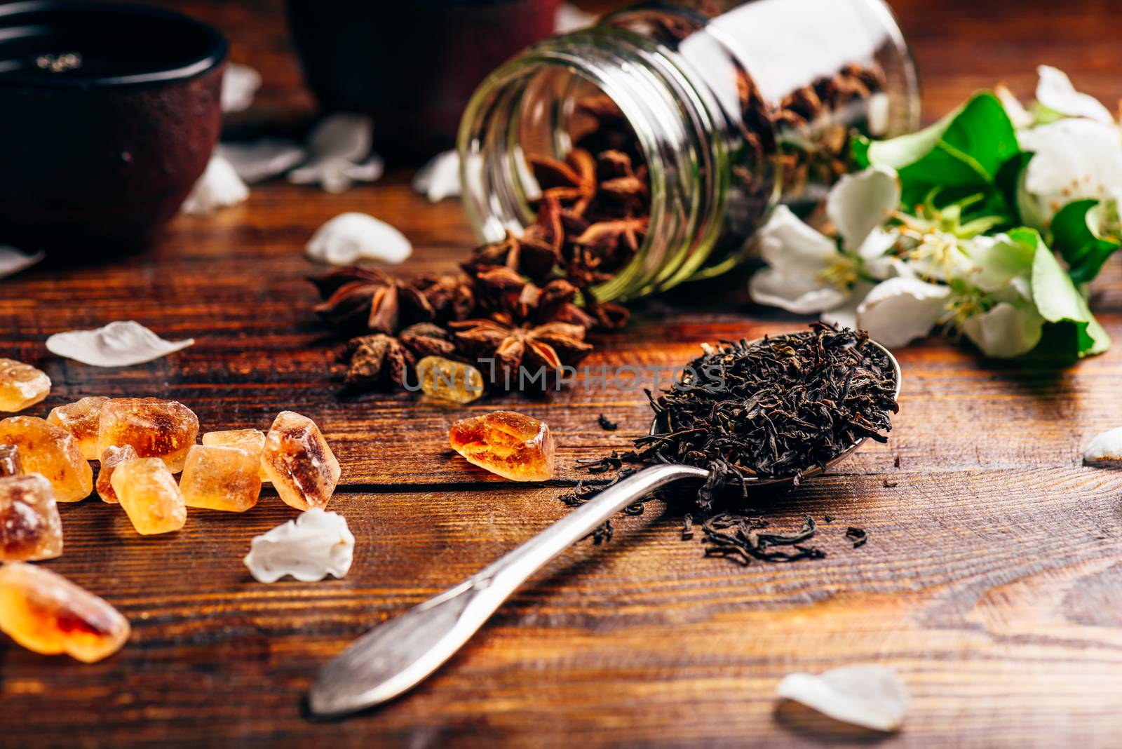 Spoonful of Tea, Apple Flowers, Sugar and Scattered Anise Star on Wooden Table.