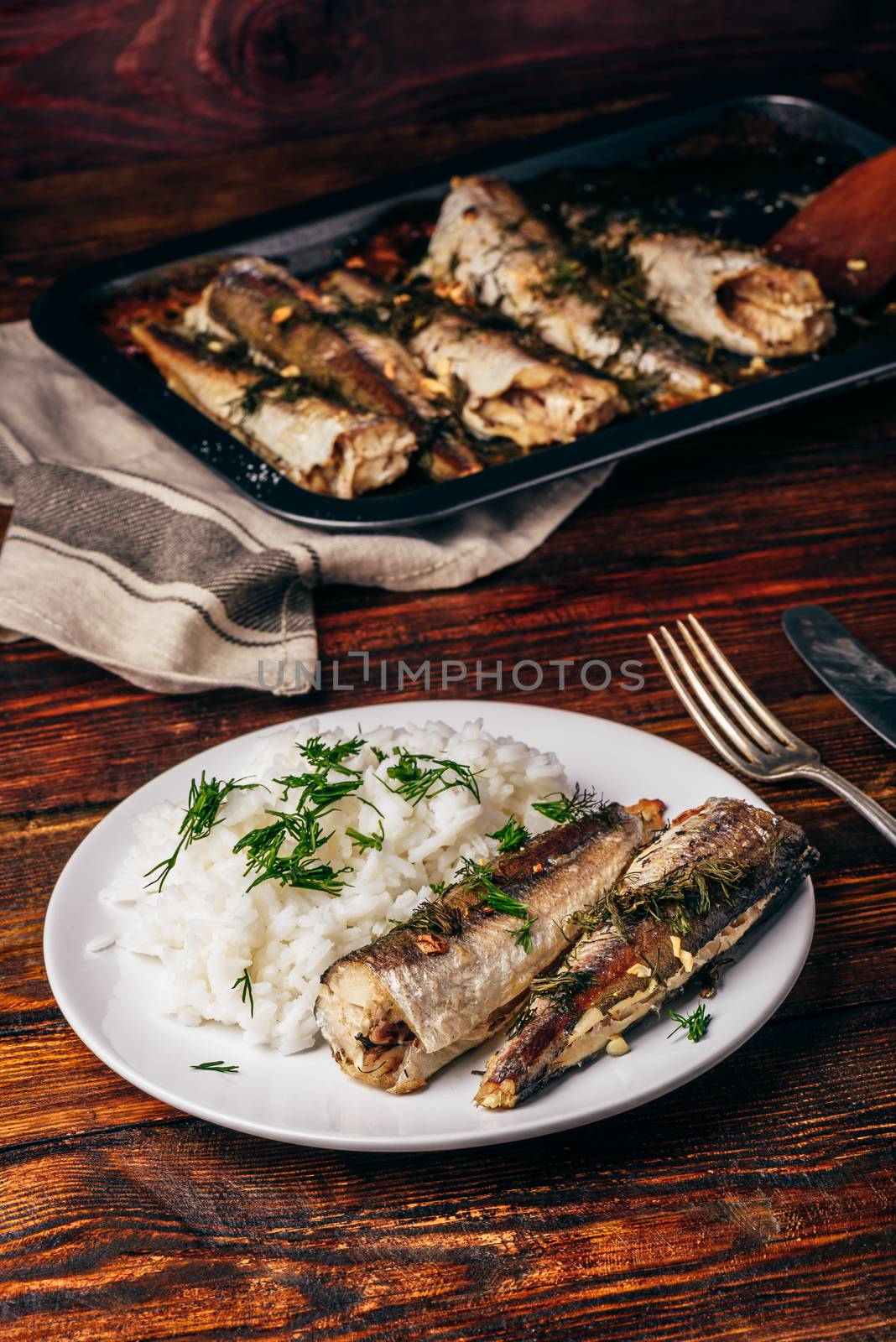 Baked hake carcasses with rice on white plate