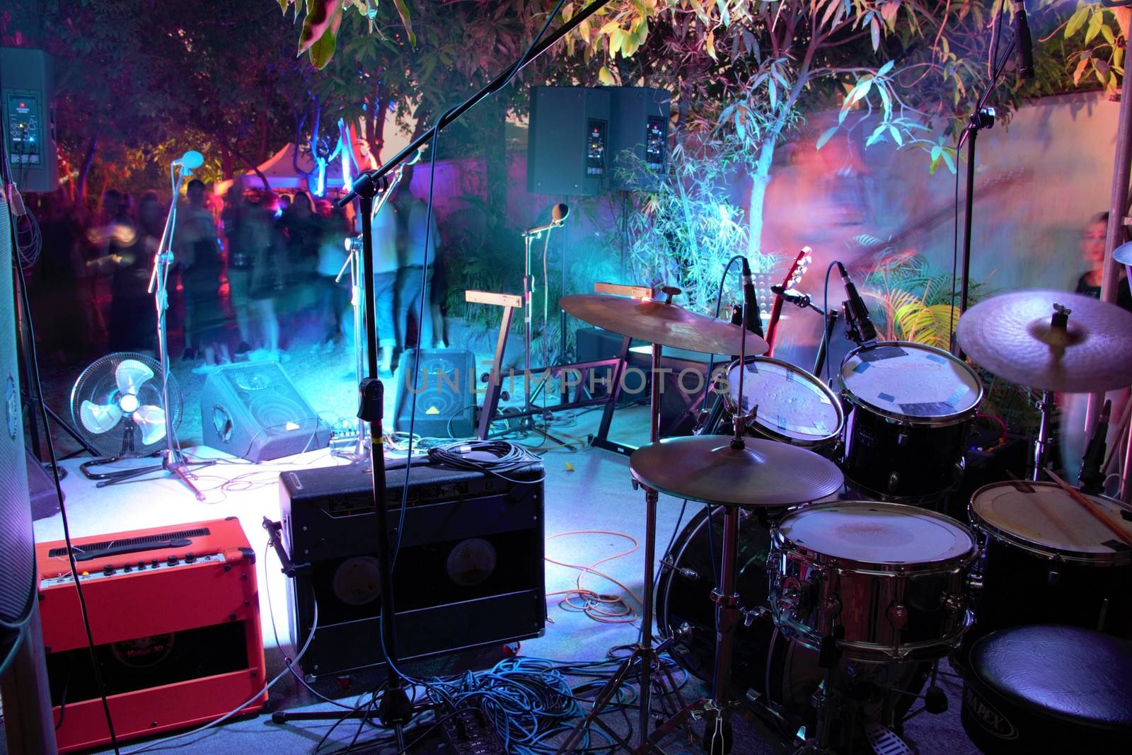 Drum set and guitar amps looking out on stage and into the audience at a small gig