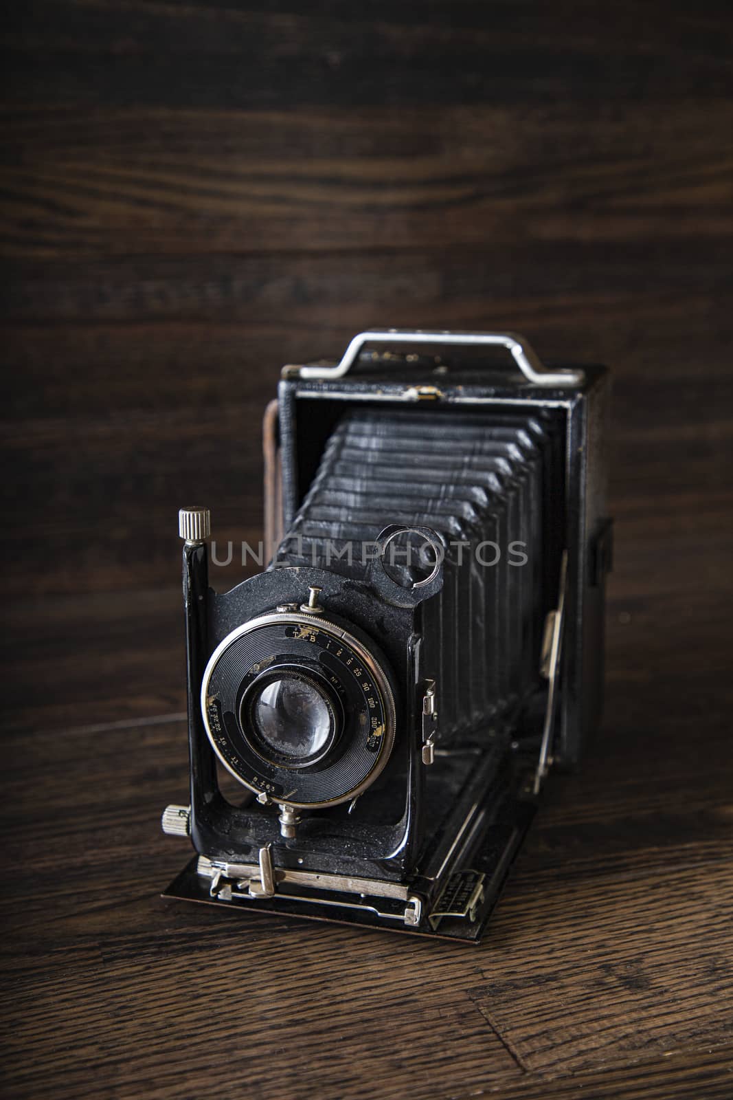 old antique medium range camera against a dark wood background