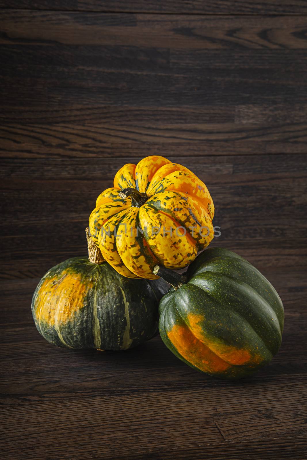 two Sweet Dumpling squash and one Kabocha squash in a stack against a wood background