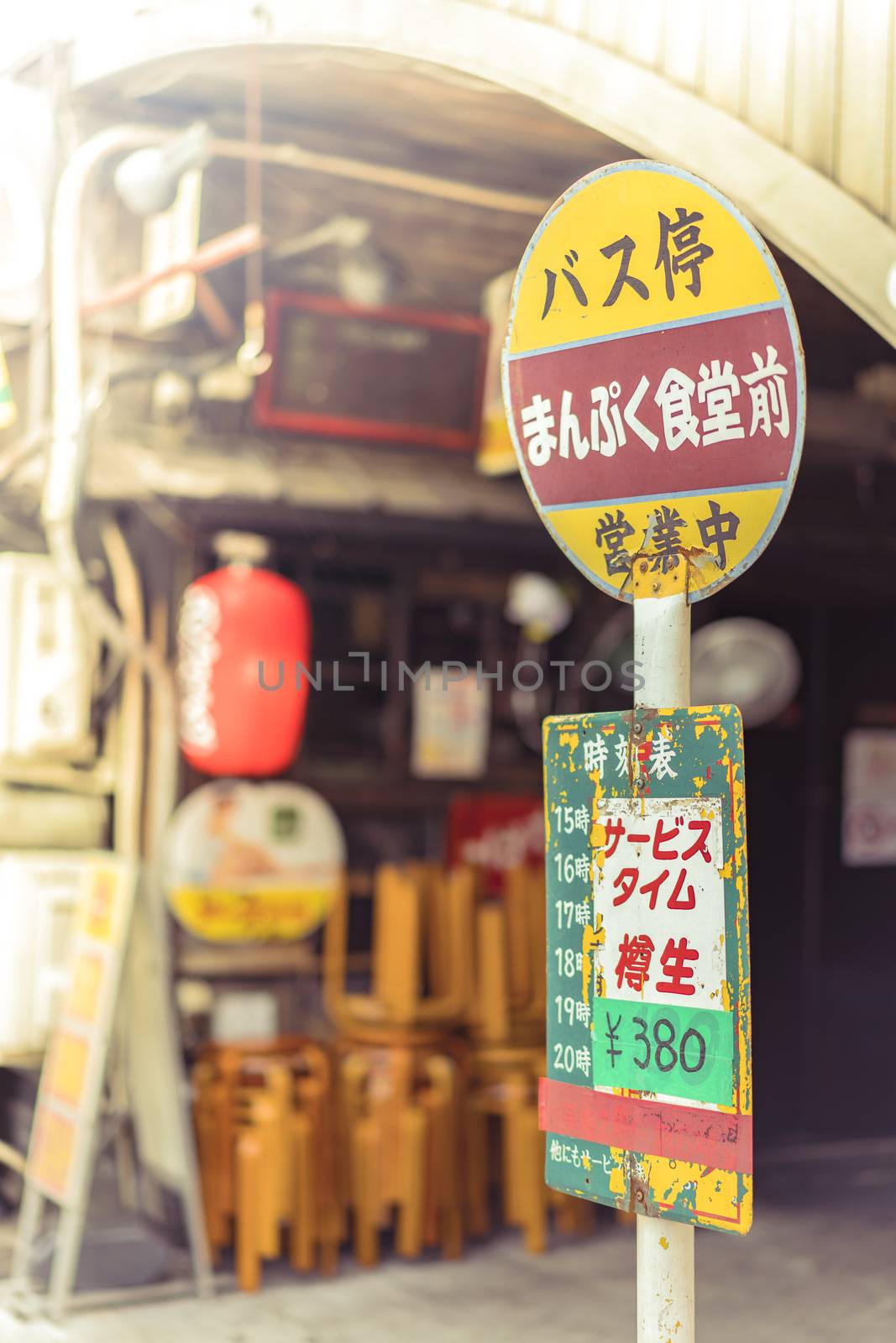 Restaurant sign immitating an old retro bus stop sign on underpass Yurakucho Concourse wall under the railway line of the station Yurakucho. Japanese noodle stalls and sake bars revive the nostalgic years of Showa air with old posters and placards glued to the walls of the tunnel.