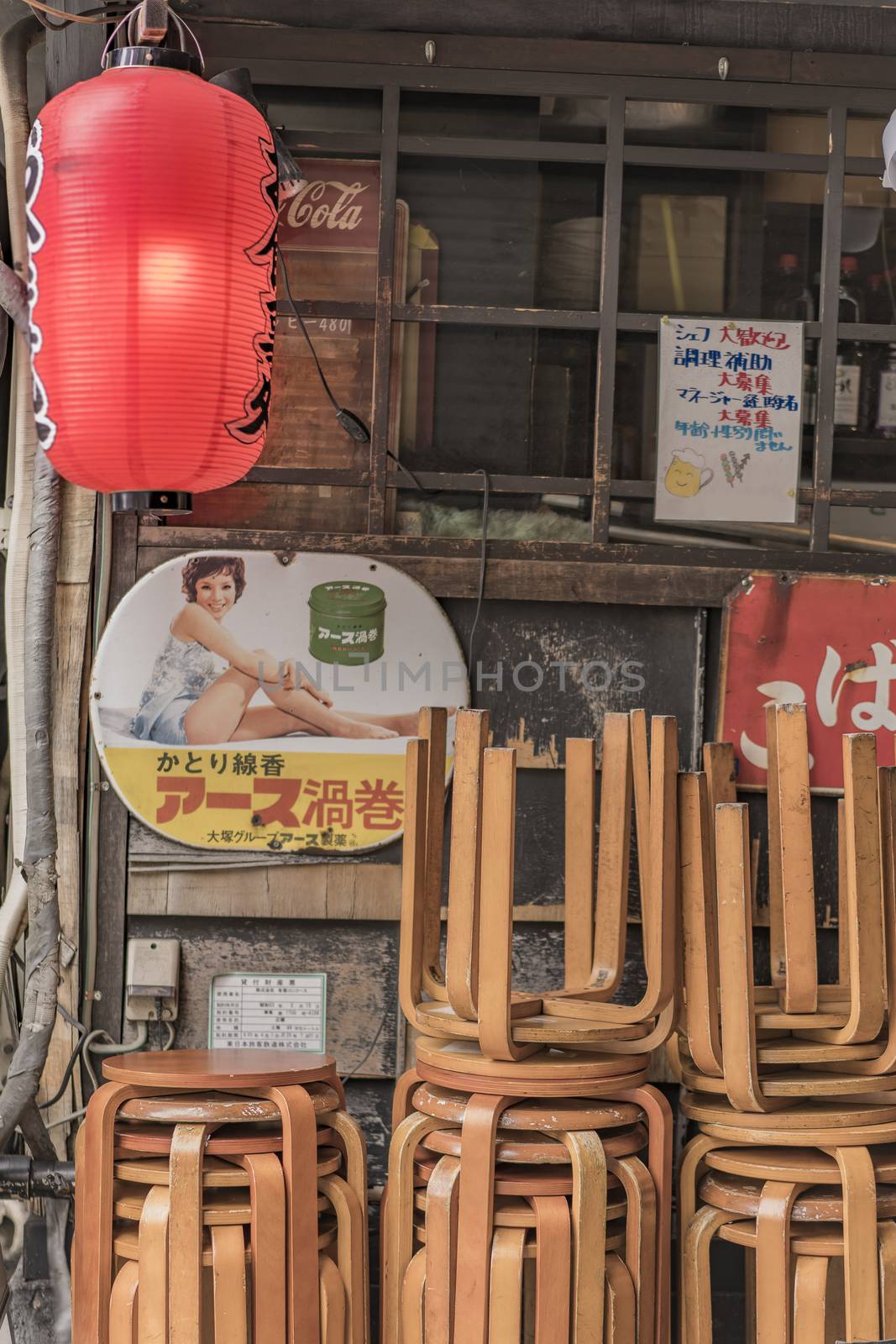 Old vintage retro japanese metal signs and red rice paper lantern where it is written "Oshokujidokoro" which means "Meal" on underpass Yurakucho Concourse wall under the railway line of the station Yurakucho. Japanese noodle stalls and sake bars revive the nostalgic years of Showa air with old samurai posters and placards glued to the walls of the tunnel.