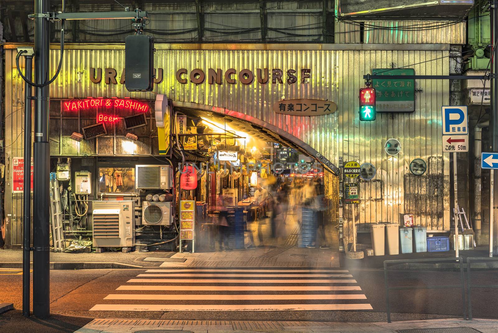 Night view of the Yurakucho Concourse underpass under the railway line of the station Yurakucho. Japanese noodle stalls and sake bars revive the nostalgic years of Showa air with old posters and placards glued to the walls of the tunnel.