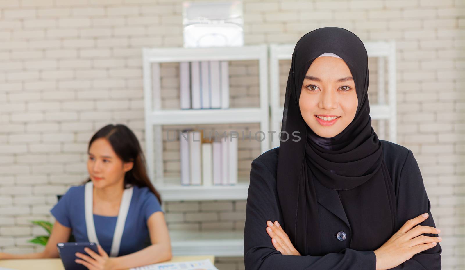 Two Muslim businesswomen are discussing company earnings happily in the modern office.