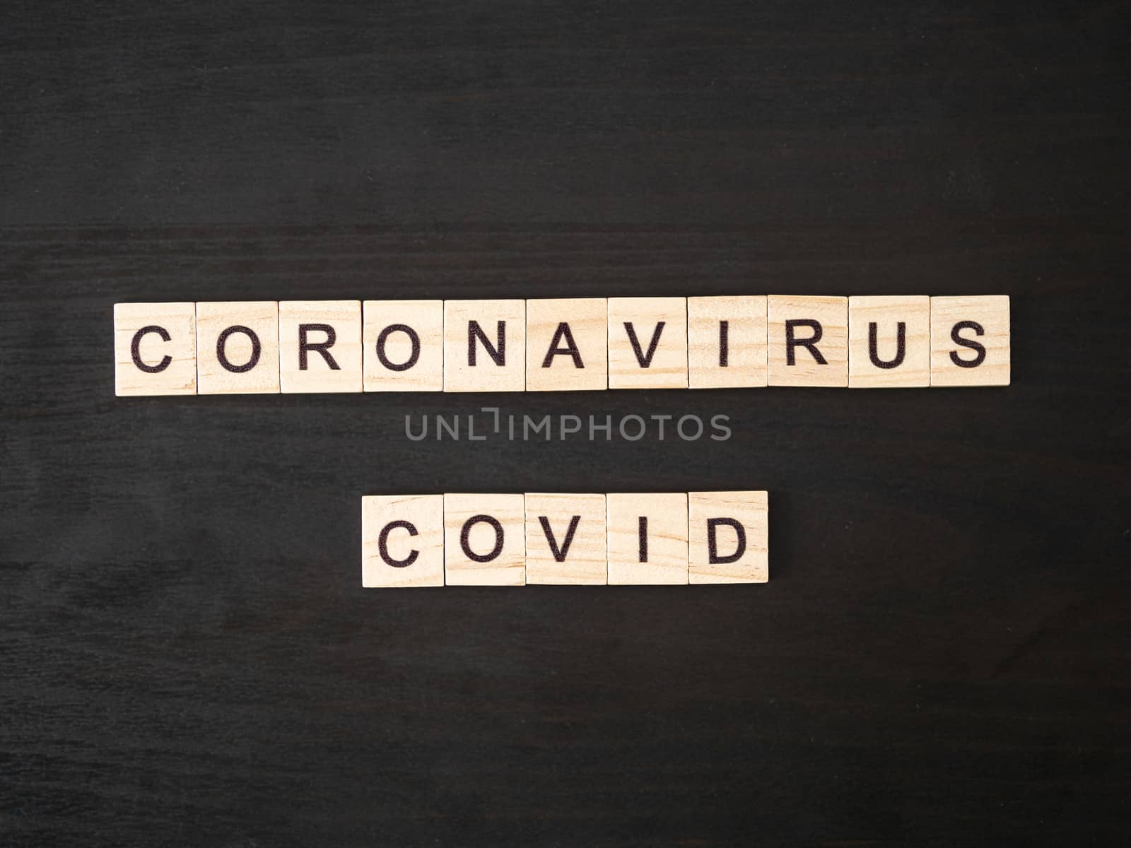 Coronavirus COVID words made of wood block. Coronavirus COVID text on dramatic atmosphere black wooden table. Coronavirus concept top view.