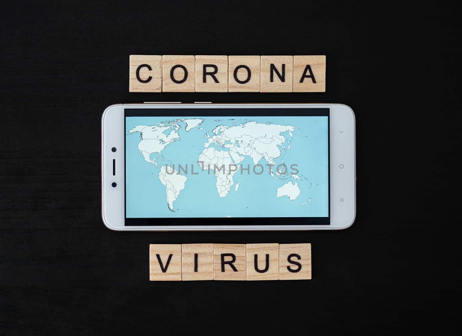 Coronavirus word made of wood block and world map on smartphone screen. Coronavirus text on dramatic atmosphere black wooden table. Coronavirus concept top view.