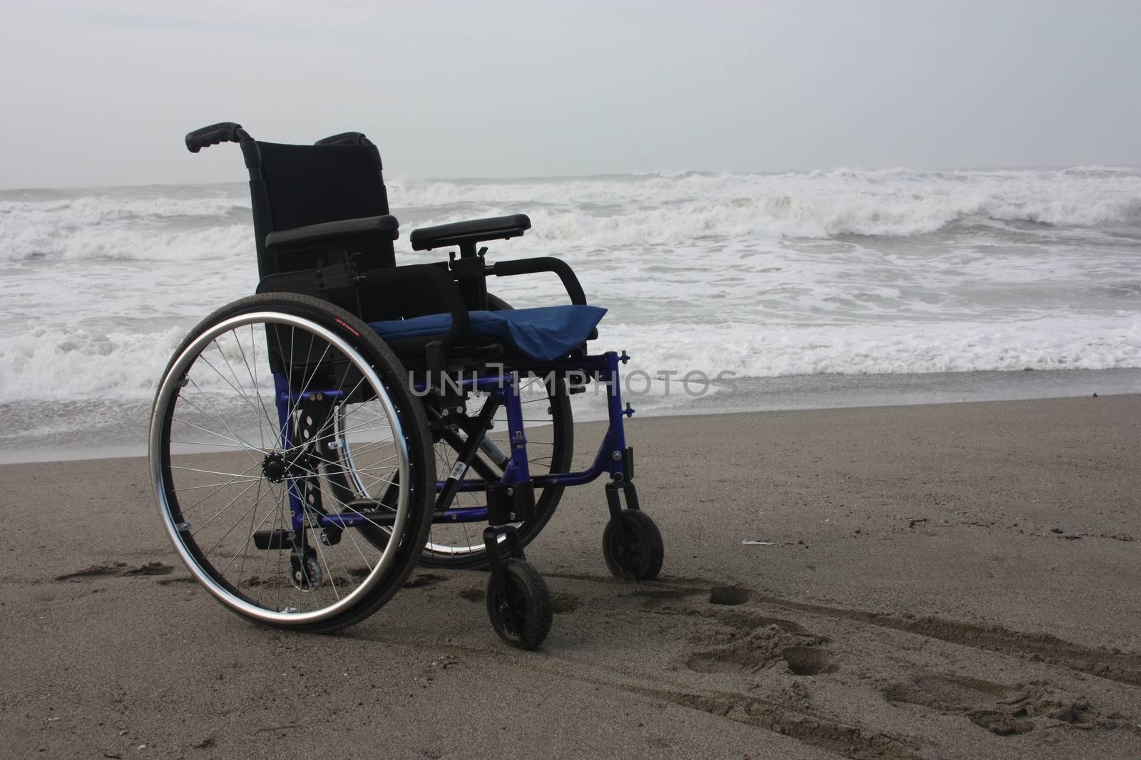 wheelchair left alone on a beach by the sea in winter without sick or other people