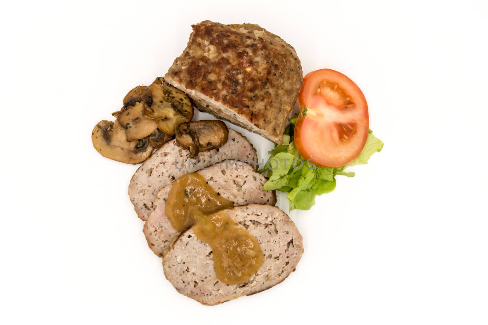 Meatloaf cut into slices with mushrooms, tomato and salad top view on an isolated white background.