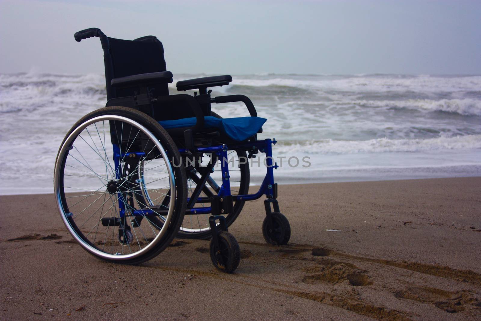 wheelchair left alone on a beach by the sea in winter without sick or other people