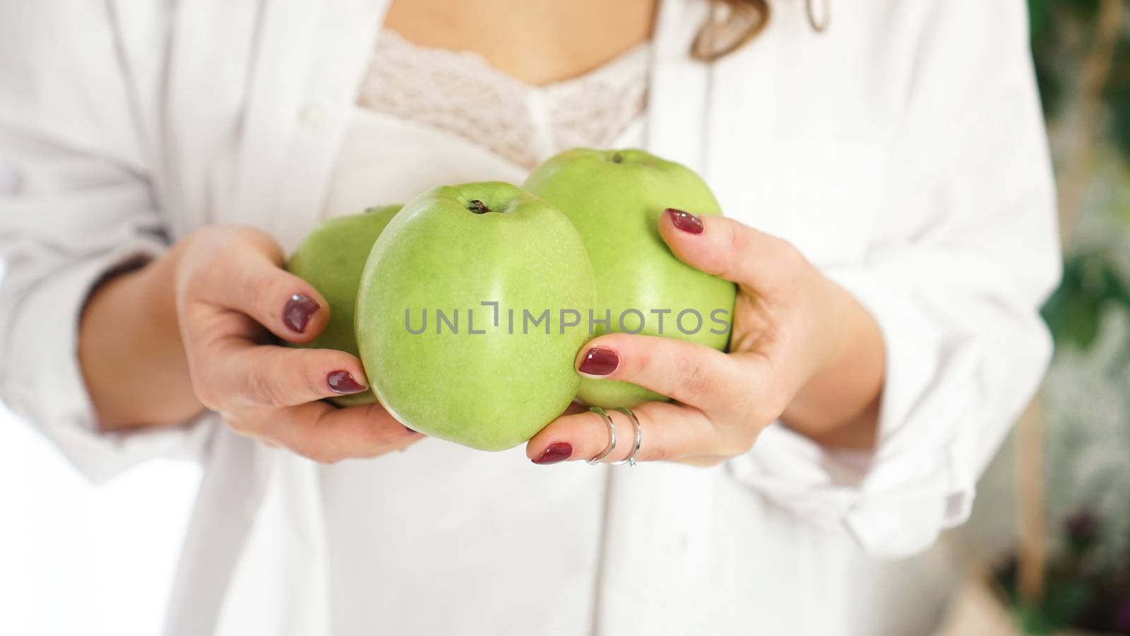 Close up photo of female hands holding three green apples