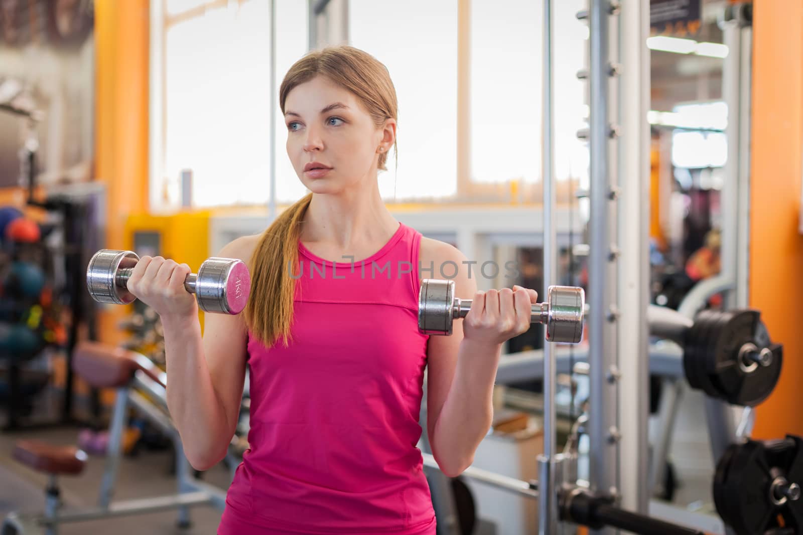 Active woman lifting dumbbells in the gym