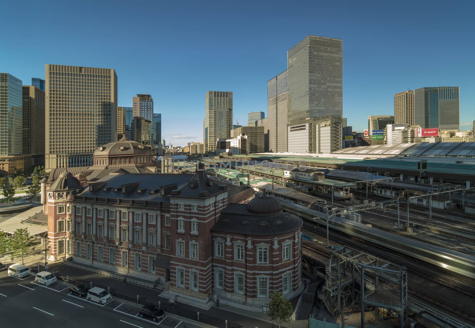 Marunouchi side of Tokyo railway station in the Chiyoda City, Tokyo, Japan.  The station is divided into Marunouchi and Yaesu sides in its directional signage. The station first called Central Station was built in 1914 directly in front of the Imperial Palace gardens. The three-story station building was designed by architect Tatsuno Kingo who also designed Manseibashi Station and the nearby Bank of Japan building. Much of the station was destroyed in B-29 firebombing on May 25, 1945. The bombing shattered the impressive rooftop domes. The station was quickly rebuilt within the year, but simple angular roofs were built in place of the domes, and the restored building was only two stories tall instead of three. 