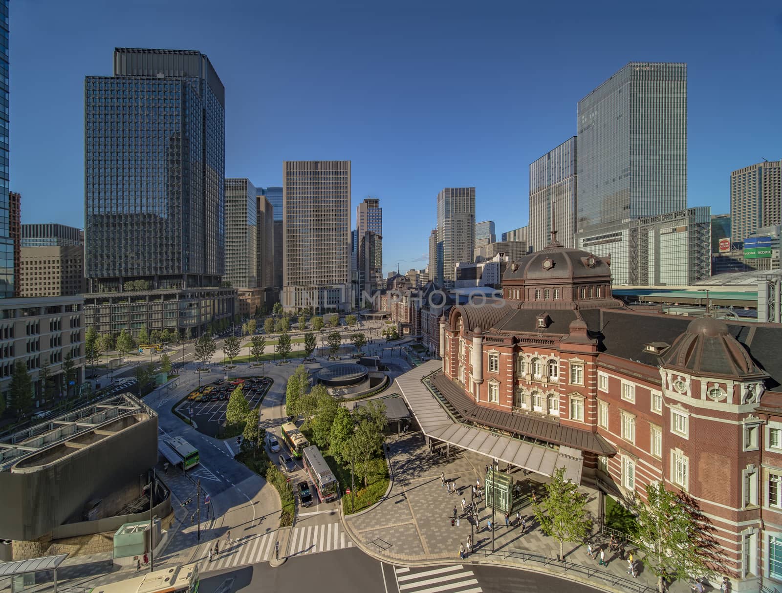 Marunouchi side of Tokyo railway station in the Chiyoda City, Tokyo, Japan.  The station is divided into Marunouchi and Yaesu sides in its directional signage. The station first called Central Station was built in 1914 directly in front of the Imperial Palace gardens. The three-story station building was designed by architect Tatsuno Kingo who also designed Manseibashi Station and the nearby Bank of Japan building. Much of the station was destroyed in B-29 firebombing on May 25, 1945. The bombing shattered the impressive rooftop domes. The station was quickly rebuilt within the year, but simple angular roofs were built in place of the domes, and the restored building was only two stories tall instead of three. 