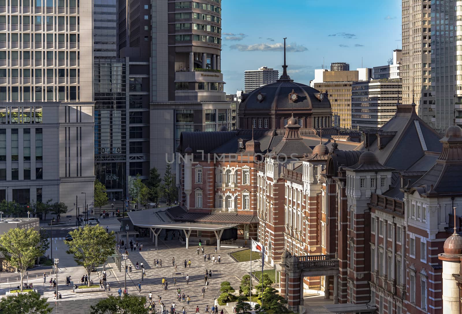 Marunouchi side of Tokyo railway station in the Chiyoda City, Tokyo, Japan.  The station is divided into Marunouchi and Yaesu sides in its directional signage. The station first called Central Station was built in 1914 directly in front of the Imperial Palace gardens. The three-story station building was designed by architect Tatsuno Kingo who also designed Manseibashi Station and the nearby Bank of Japan building. Much of the station was destroyed in B-29 firebombing on May 25, 1945. The bombing shattered the impressive rooftop domes. The station was quickly rebuilt within the year, but simple angular roofs were built in place of the domes, and the restored building was only two stories tall instead of three. 