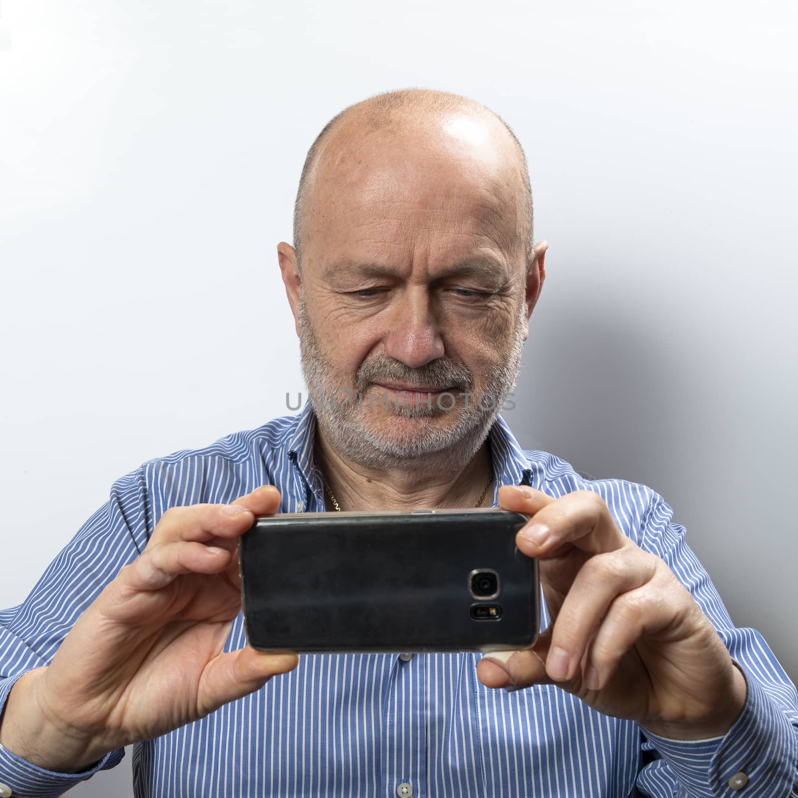 A middle-aged man takes a photograph with his cell phone