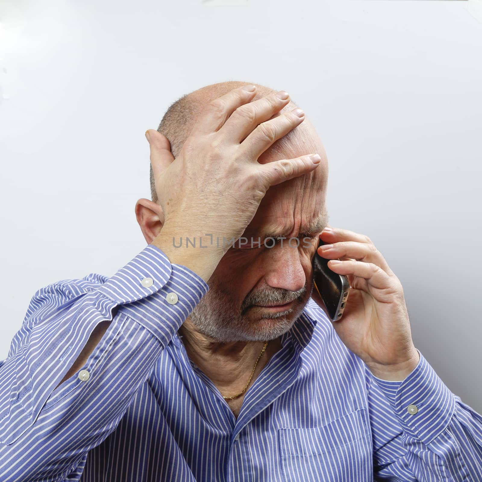 A middle-aged man worried while talking on a cell phone