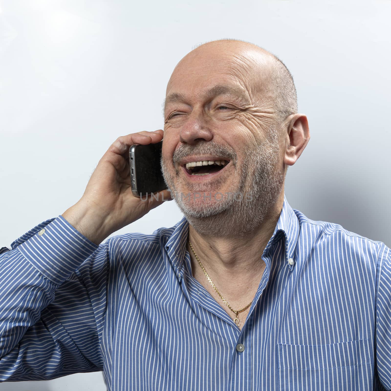 A middle-aged man laughs during a cell phone conversation