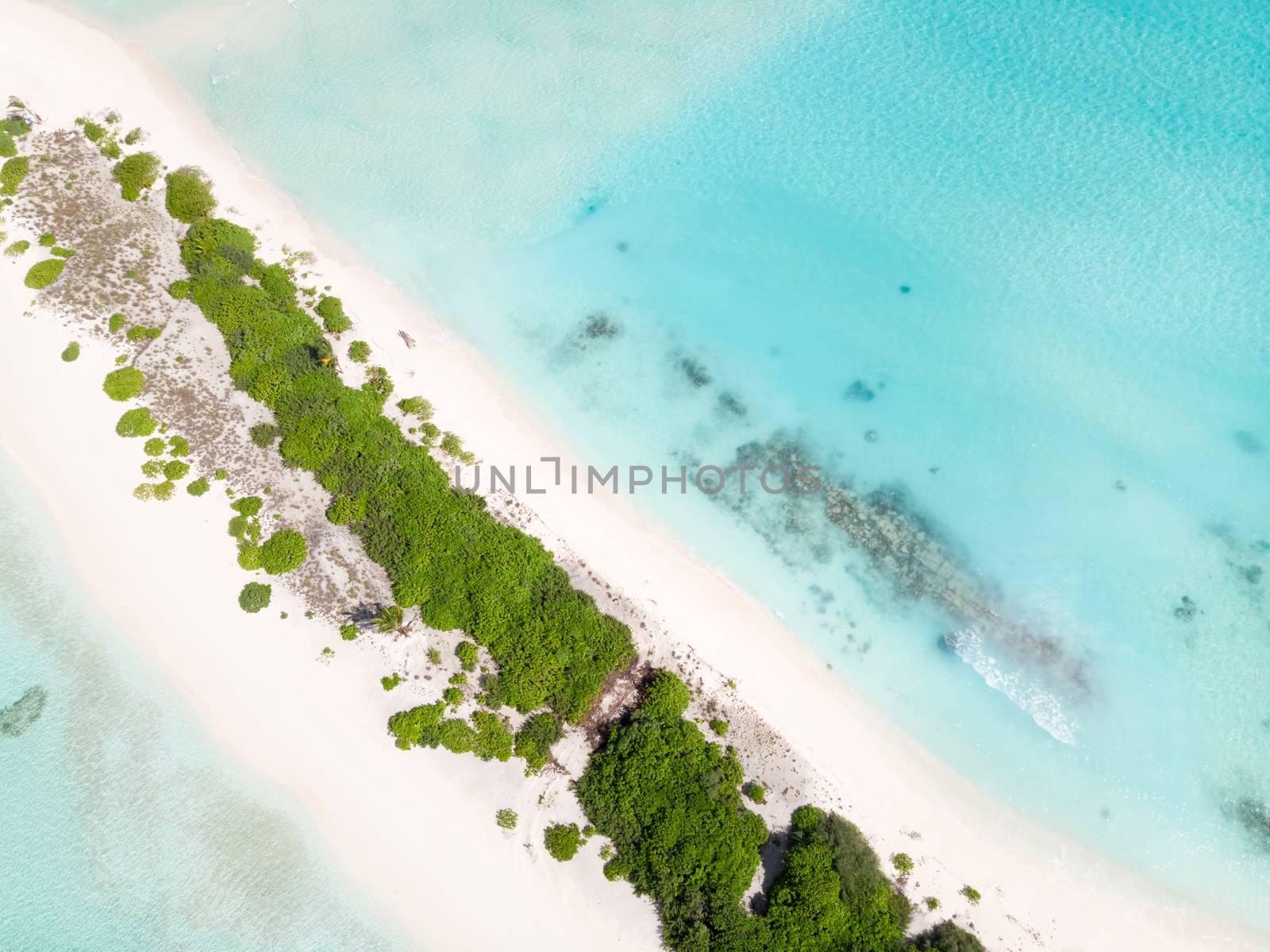 Aerial drone view of picture perfect beach and turquoise lagoon on small tropical island on Maldives.
