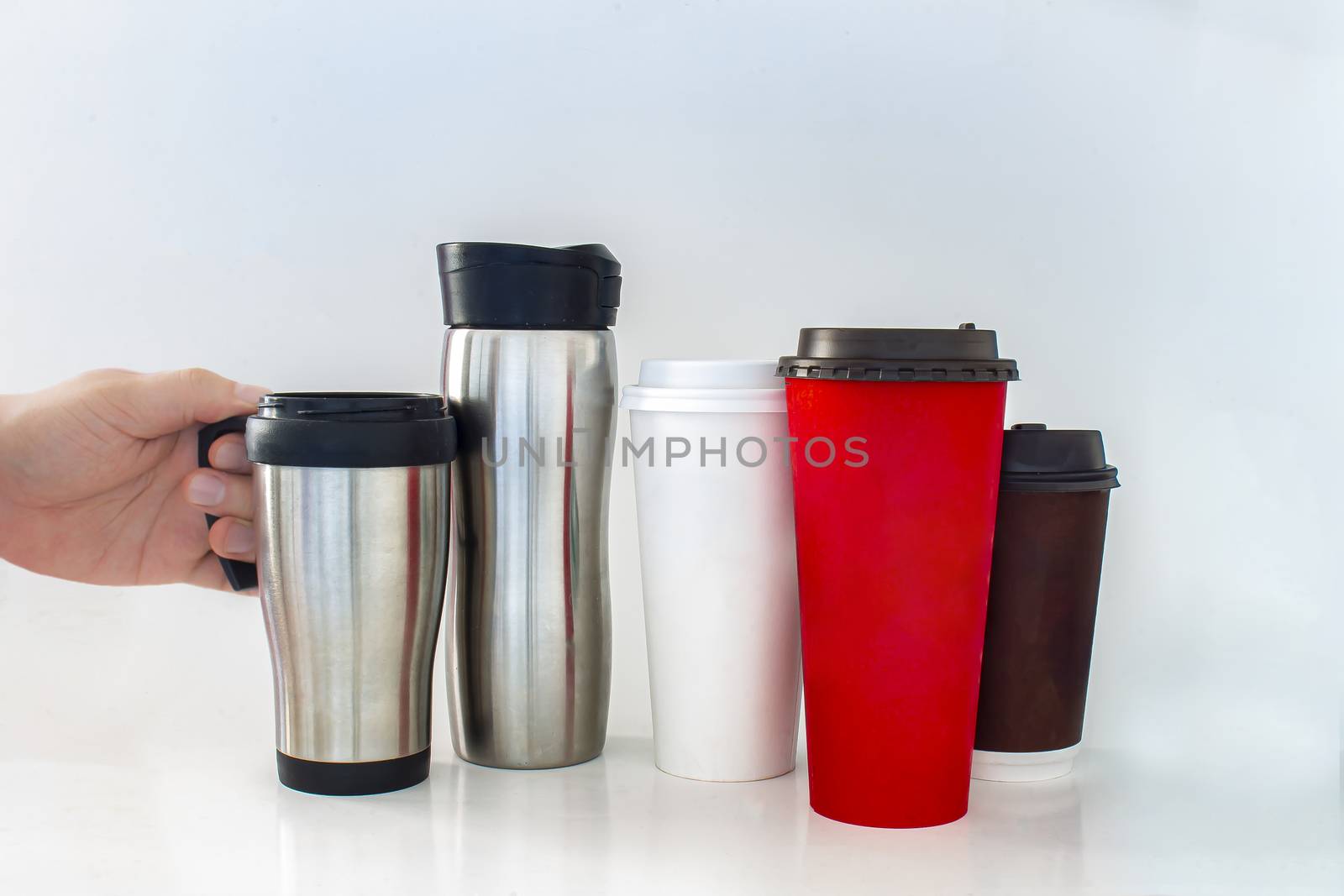 A person holding a to go coffee cup next to Single Use Coffee Cup on a white background.