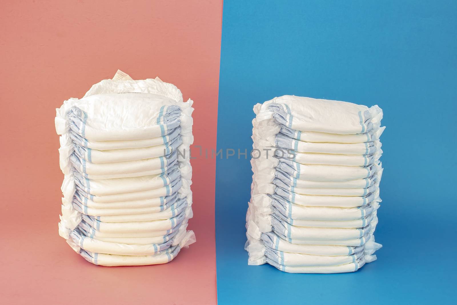 A couple of diapers stack on a blue and pink background