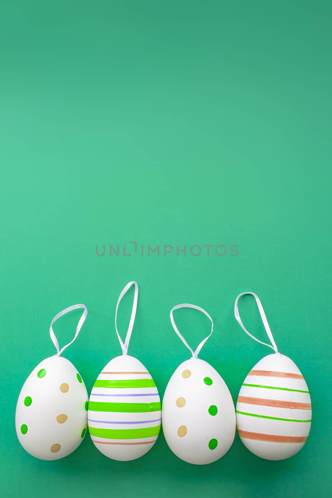 Colorful easter eggs with a hanger on a green background with soft shadows