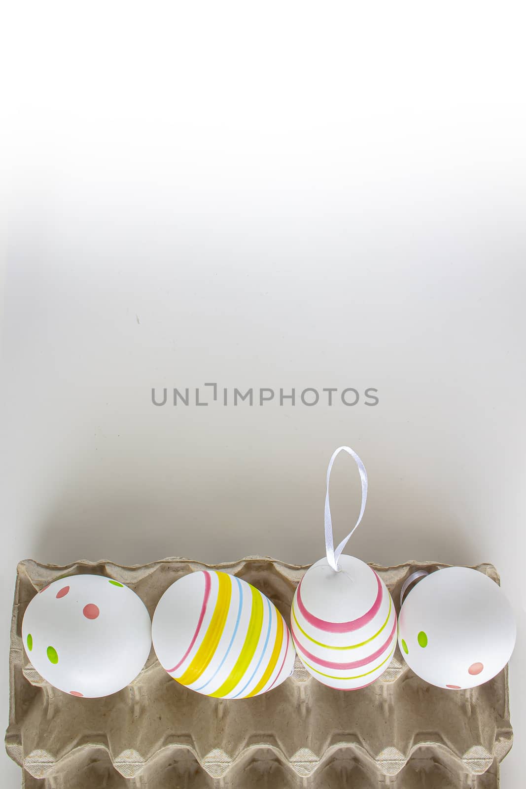 Colorful easter eggs on a cardboard holder with a white background and soft shadows by oasisamuel