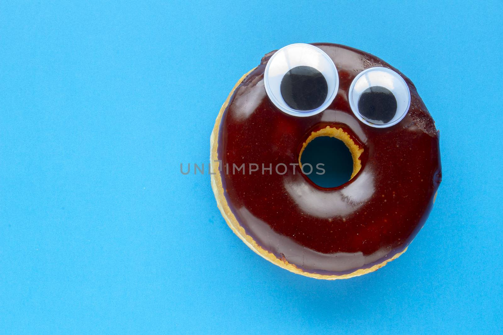 A Tim Hortons Chocolate Dip Donut with Black Wiggle Googly Eyeballs on a blue background