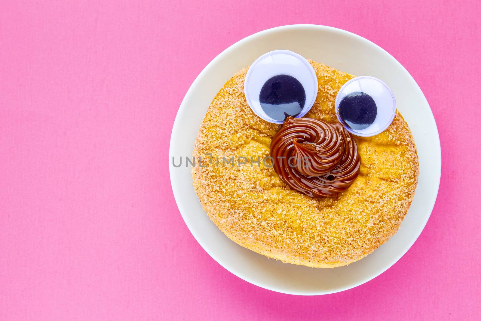 A Tim Hortons Dulce de Leche Donut with Black Wiggle Googly Eyeballs on a plate with pink background by oasisamuel