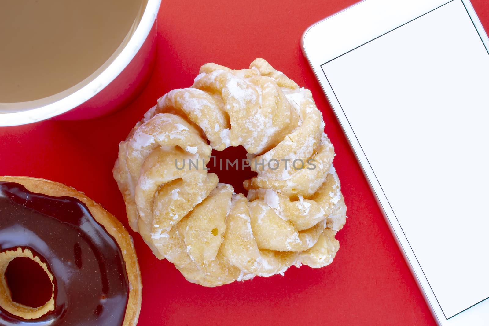 A cup of coffee with a Chocolate Dip Donut and Honey Cruller Donut with a smartphone