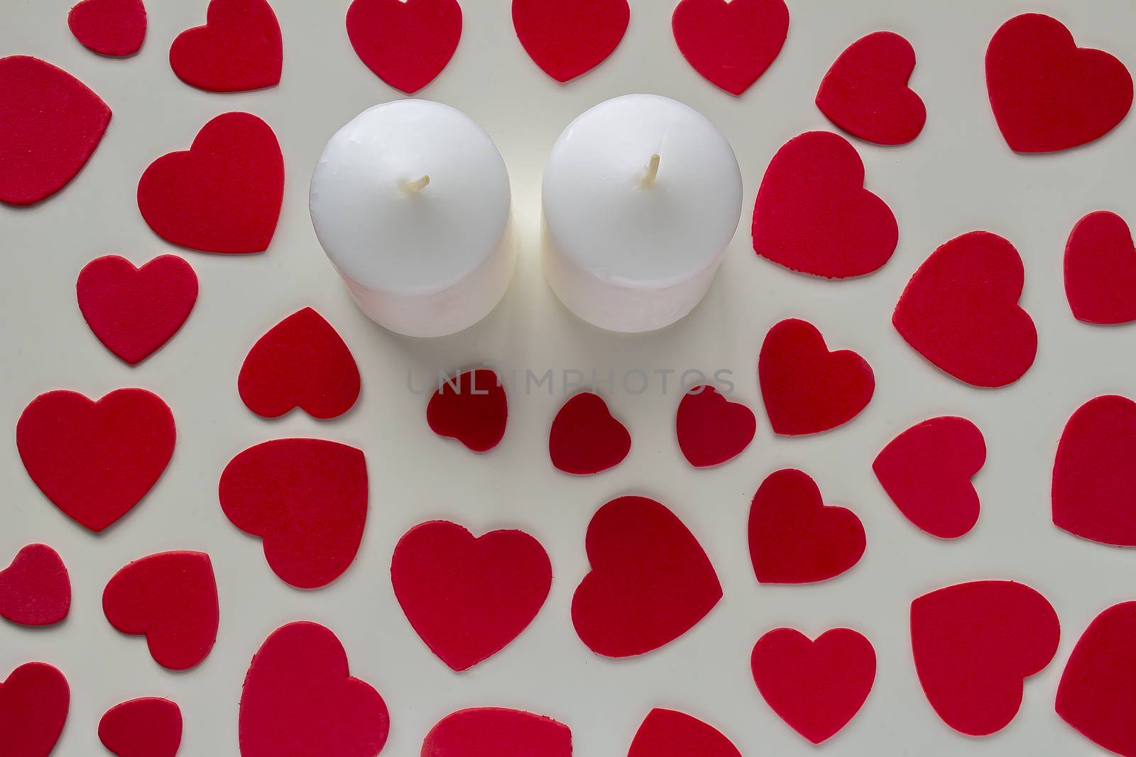 A couple of candles with red hearts around with a shadow