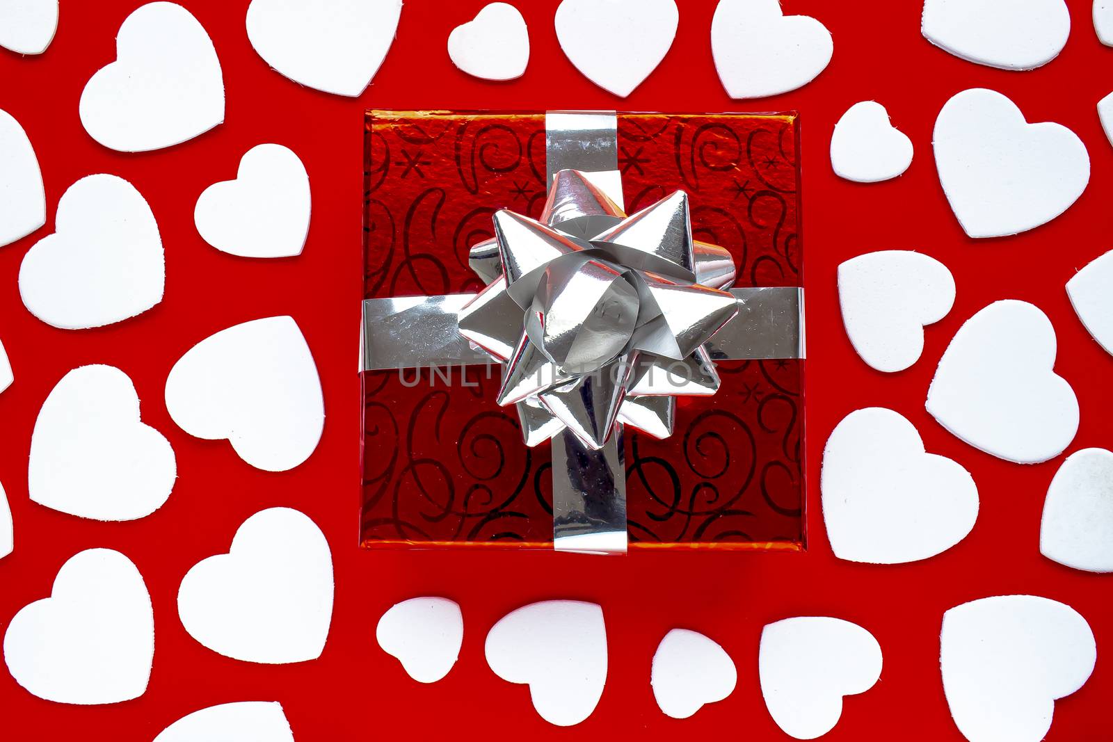 A present on a red background with white hearts. For Valentine’s Day by oasisamuel