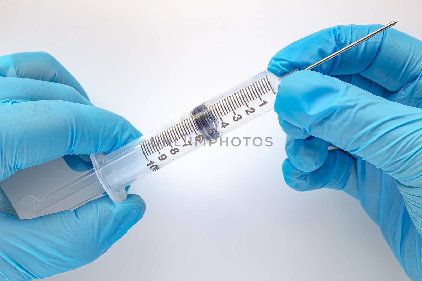 Doctor or nurse with a full syringe in blue gloves on a white background. Concept vaccines, hospital and disease by oasisamuel