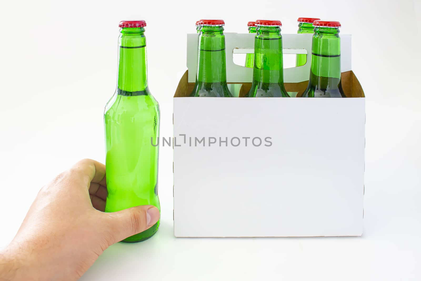 A person holding a beer with a six pack of a green beer bottles isolated on white background by oasisamuel
