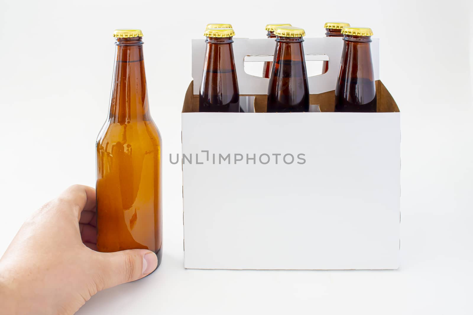 A person holding a beer with a six pack of a brown beer bottles isolated on white background