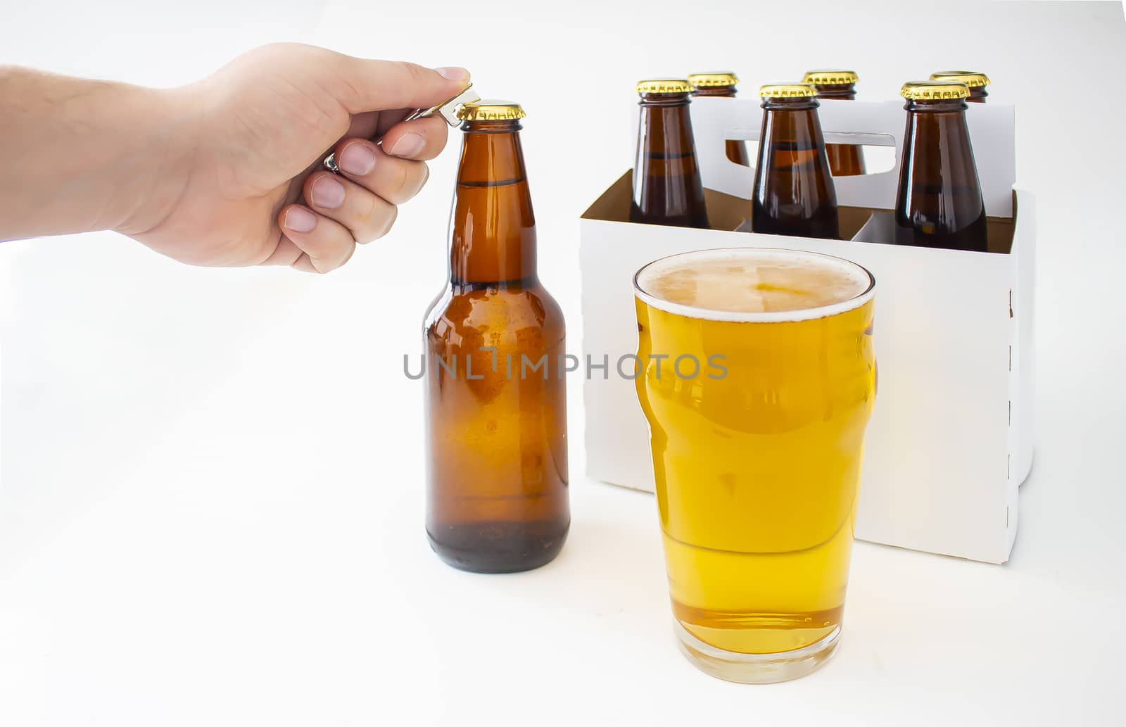 A person opening a Pilsner Style Lager brown bottle sic pack with a full pint of beer by oasisamuel