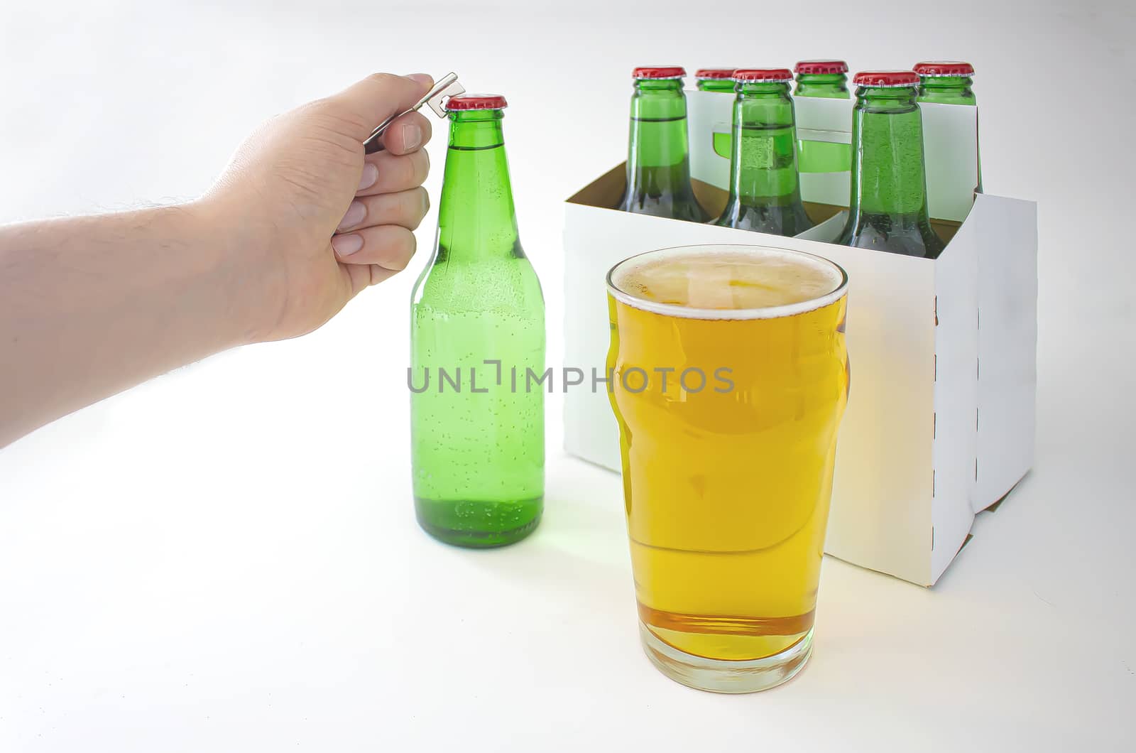 A person opening a Pilsner Style Lager green bottle sic pack with a full pint of beer by oasisamuel