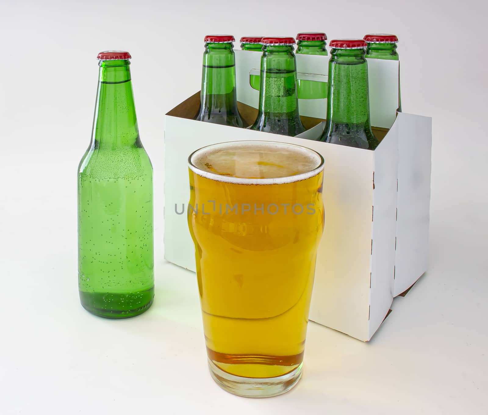 A six green bottle pack of pilsner beer with a full pint of beer