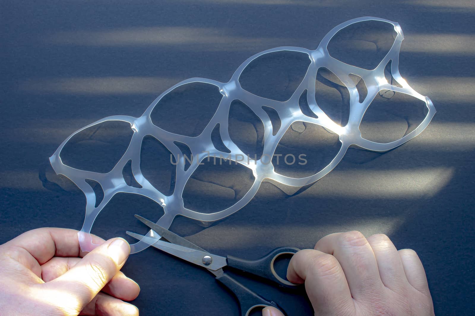 A person cutting a eight pack rings or eight pack yokes with scissors by oasisamuel