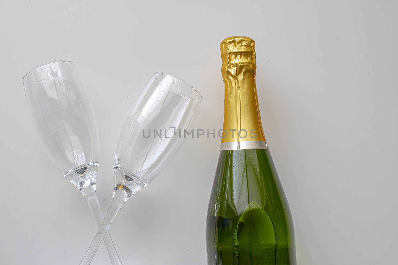 Unopened champagne bottle with cups on a white background