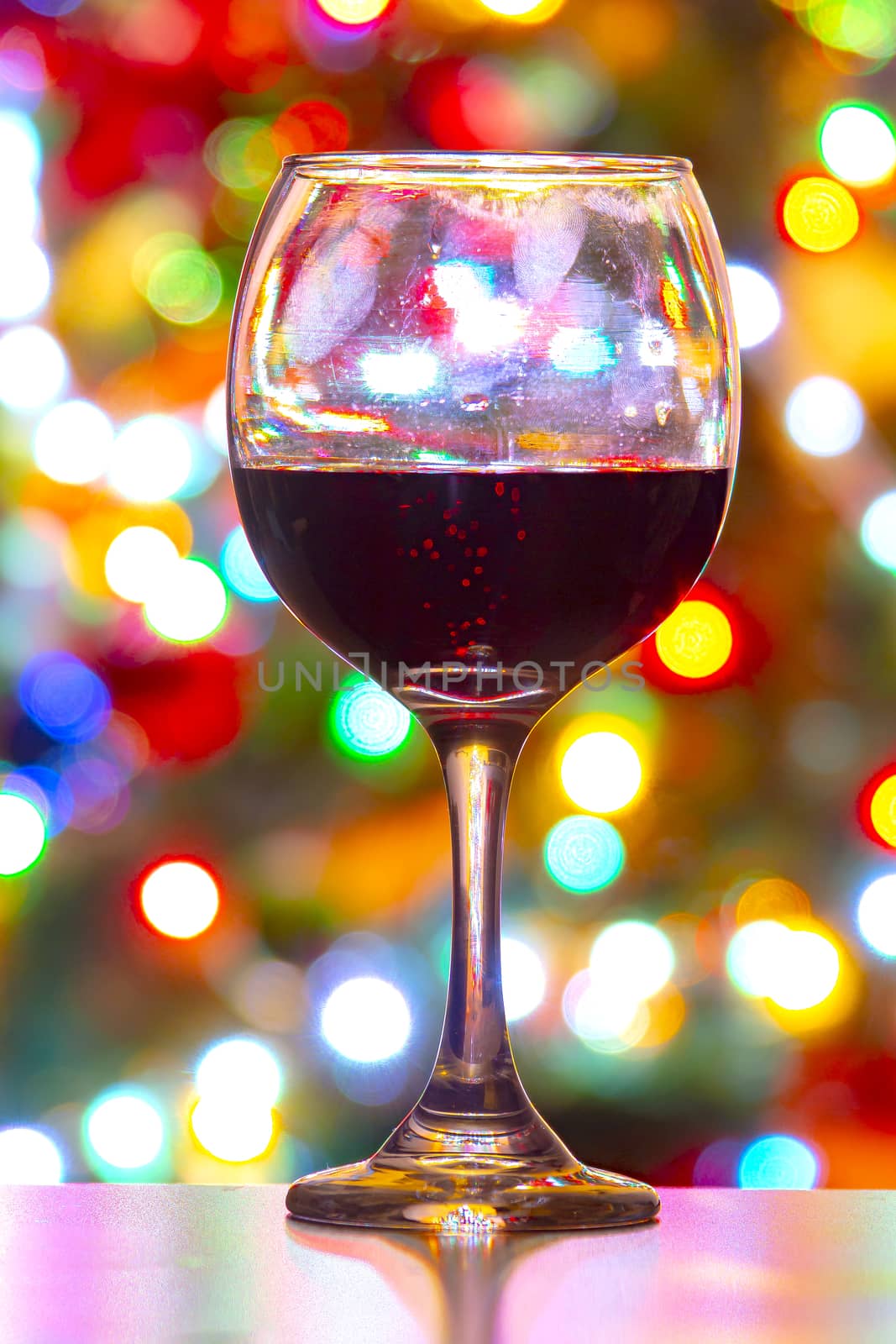A cup of red wine with christmas lights on the background