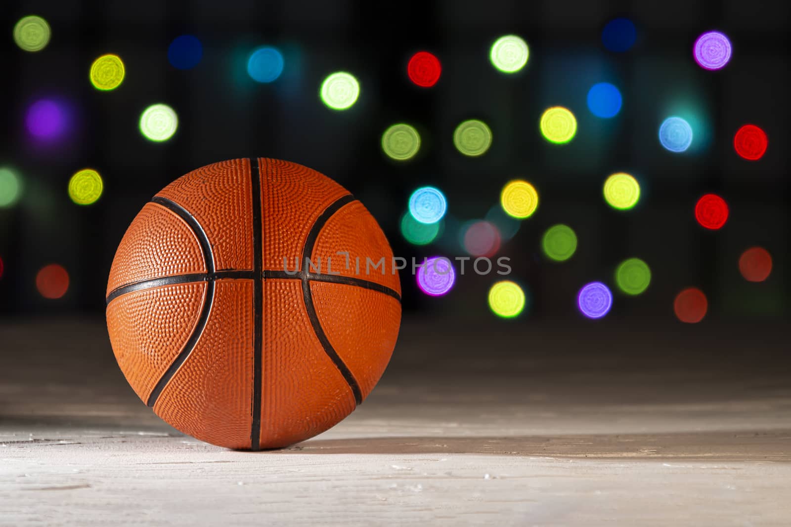 Basketball on a texture surface with defocus colourful lights on the background.